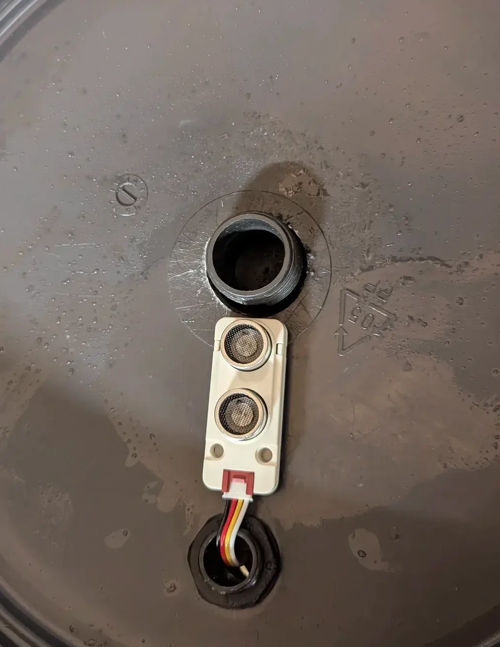 The ultrasonic distance sensor installed on the top cover of the tank.